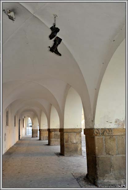 Klenuté podloubí s párem zavěšených bot